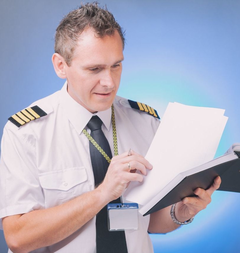 Piloto en uniforme revisando un libro de vuelo